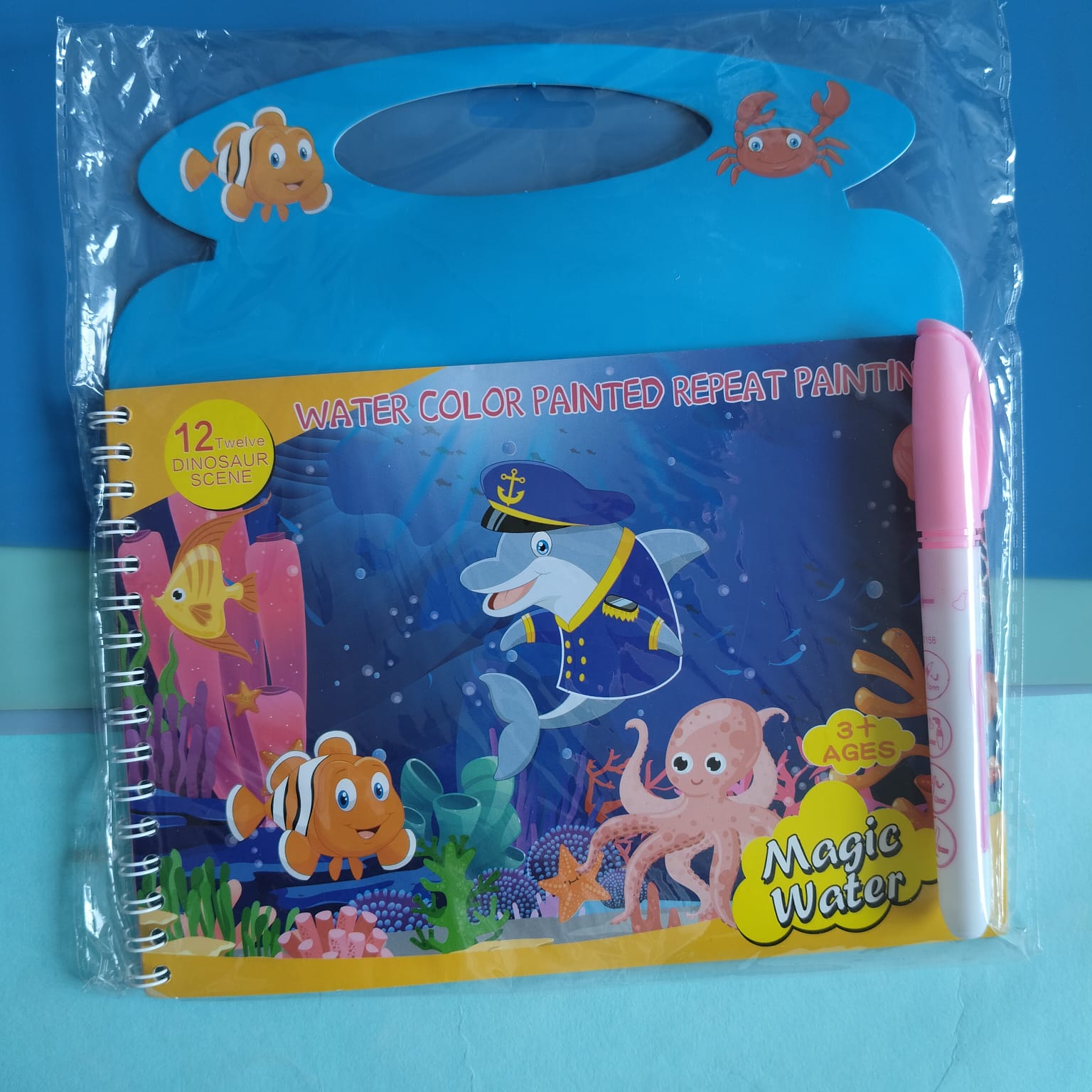 Children's coloring book with ocean-themed illustrations and a pen, on a blue background.